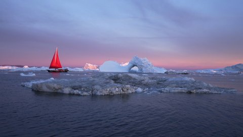 Red boat sailing near icebergs against sky - Disko Bay, Greenland