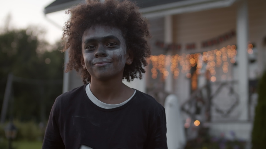 Close up of African teenager with curly hair dressed in skeleton costume looking at camera and smiling