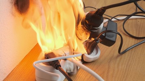 power strip with electrical plugs burns with open flame in room. concept of occurrence of fire from overload by electrical appliances.