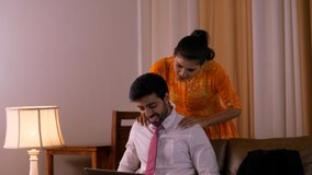 Beautiful Indian couple - Tired husband working on laptop and concerned wife messaging his shoulders. HD video clip of an Indian husband and wife at home - Husband working from home after office ho...