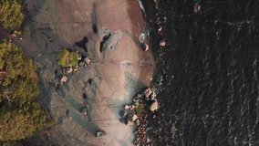 4K summer late afternoon aerial video of Santalahti Baltic Sea Finnish Bay lagoon, pine tree forest beach with red granite boulders, lone island beach near Kotka, Finland Suomi, northern Europe