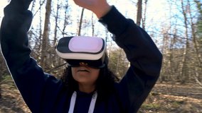 HD video clip of beautiful mixed race African American girl teenager female young woman using virtual reality VR headset in a forest woodland environment