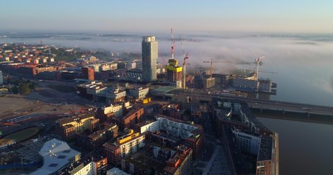 Helsinki, Aerial, tracking, drone shot, overlooking the Kalasatama cityscape, on a sunny and misty autumn morning dawn, in Helsingfors, Uusimaa, Finland