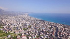 Top view of resort town located on coast. Clip. Panorama of city on mountain coast of sea on background of beautiful sky. Paradise resort with tropical climates by sea