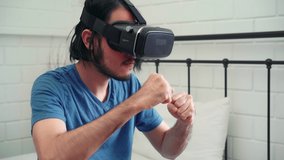 Young Asian man using glasses virtual reality simulator playing boxing game in bedroom, Japanese male feeling happy using relax time lying on bed at home. Teen play games relax at home concept.