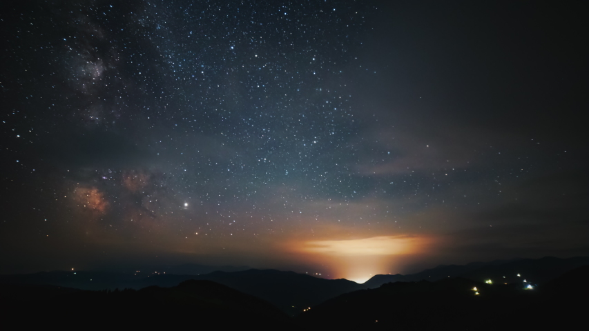 The Milky Way Galaxy moving over the mountains range in night sky full of stars, Perseids and planes traffic
