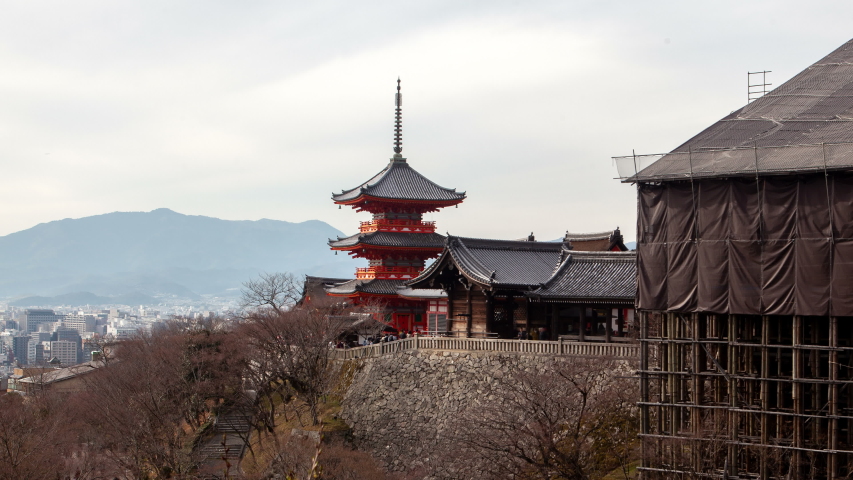 Timelapse zoom out Kyoto Kiyomizu-dera temple complex pagoda and ancient decrepit wooden building with people crowd heavy flow between Buddhism religion cultural symbols on sunny spring day