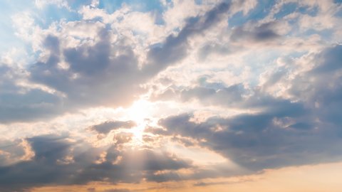 Timelapse: sun beams shining through moving dramatic white clouds. Cloudy blue sky, warm sunrise or sunset illumination, sun lens flare. Time lapse, peaceful, hope, religion, spiritual, nature concept