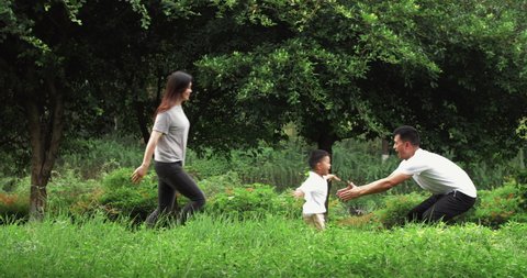 Slow motion of happy asian family playing outdoor in the Nature little boy running to his father young man holding his son high up Joyful family having fun in park with grass and tree summer day