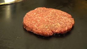 Frying a raw meat burger on a hot plate - real time video