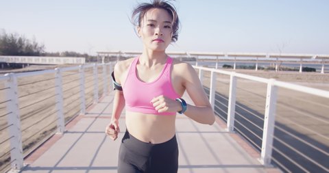 slow motion of Asian young woman run on city bridge road with smartwatch