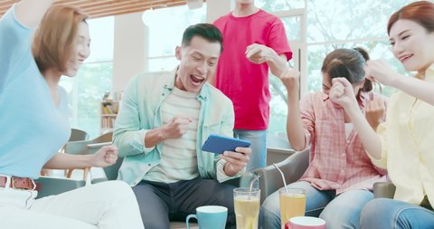 asian man play games on smart phone and friends are happily