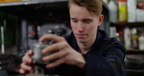 4K Trainee mechanic or student rebuilding engine in workshop