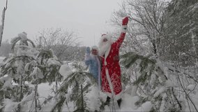 Santa Claus and granddaughter having fun in the winter pine forest