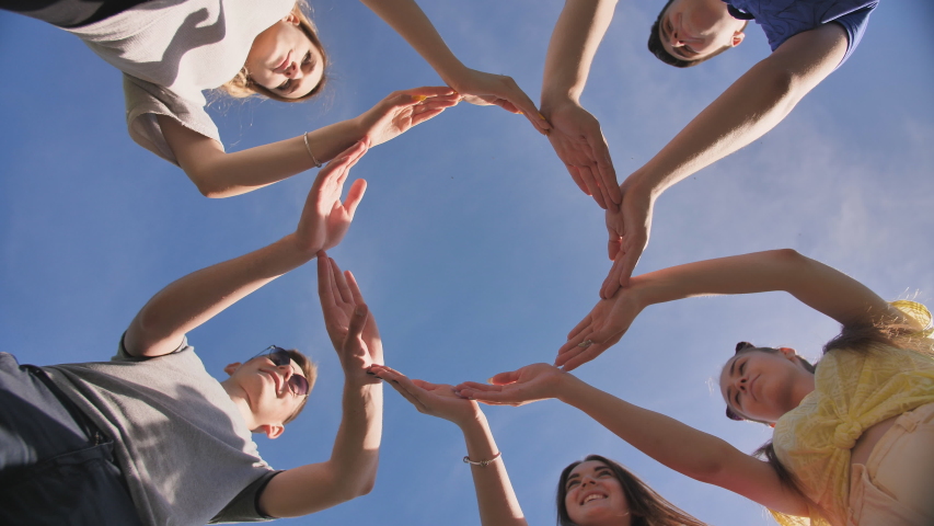 A group of friends makes a circle from the palms of their hands. | Shutterstock HD Video #1038199733
