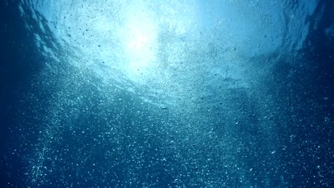 bubbles slow motion underwater coming up to surface with sun beams scenery dark blue backgrounds