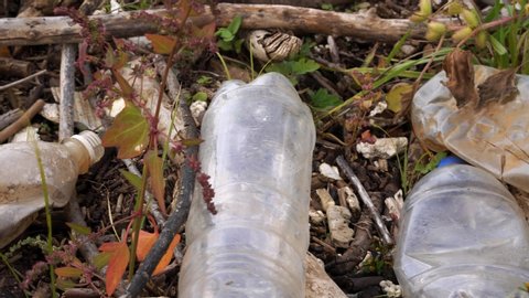 Plastic pollution of the environment. Plastic bottles and other non-degradable waste among grass.