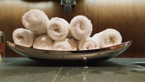 Pan Right To Left Shot Of White Rolled Hand Towels In A Metal Container Over A Marble Counter Part Of The Toilet Sink In A Very Elegant And Modern Bathroom - Wealthy Lifestyle - 4K 60fps