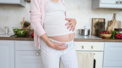 Closeup Of Pregnant Woman Belly Dancing At Home In Kitchen