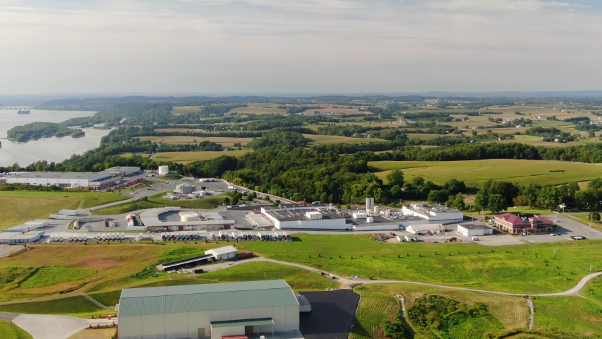 High aerial scenic view of dairy and ice cream manufacturing plant on banks of river, surrounded by Lancaster County, Pennsylvania farmland