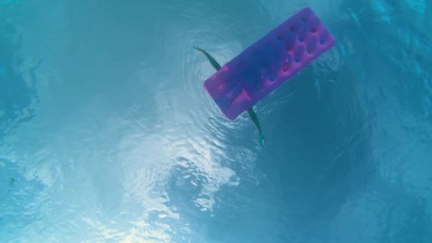 Underwater view of girl floating on air mattress inflatable bed on water in slow motion 