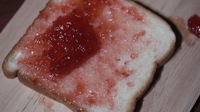Close up, slow motion clip,Applying strawberry jam on the bread.