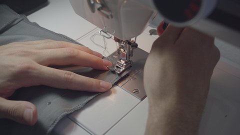 Tailor at work on sewing machine close up fashion designer