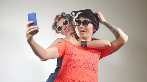 Portrait of two girls in colorful costumes take selfie on a smartphone at a party in a club. Communicating same-sex partners. Message transmission over a long distance. Date lesbians.