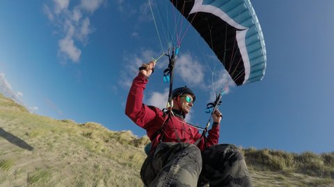 Paraglider pilot soaring in Netherlands beach, extreme sports. Adventure concept