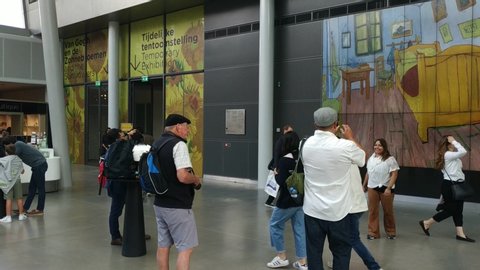 Amsterdam, Holland. August 2019. At the van gogh museum in the large entrance hall a lot of people turn between the souvenir shop and the exhibition entrance. Some take pictures. 30fps.