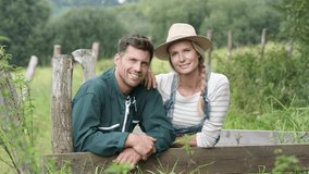 Portrait of smiling couple of farmer standing by fence
