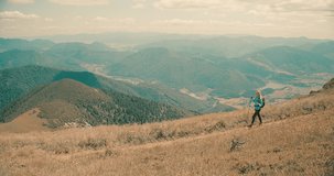 Woman backpacker tourist traveler camper walking on the top of mountain in summer sunny day under sun light. Beautiful mountains landscape view. 4K slow motion video
