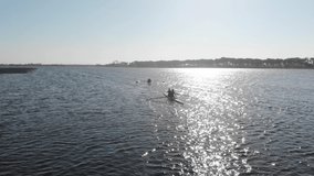 Zoom in follow shot of a team of four young adult Caucasian women rowing in two racing shells on a river during training in slow motion - Powered by Shutterstock - Get 15% off with code: PIKWIZARD15