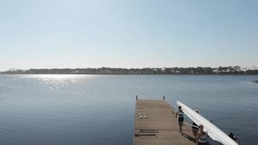 Elevated view of a team of four young adult Caucasian rowers carrying a racing shell on their shoulders on a jetty before training on a river in slow motion - Powered by Shutterstock - Get 15% off with code: PIKWIZARD15