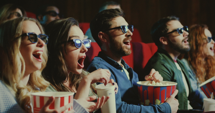 Two Caucasian young and beautiful women and two handsome men in 3D glasses with popcorn and drinks sitting in the cinema and watching an interesting action movie. Close up. | Shutterstock HD Video #1038255677