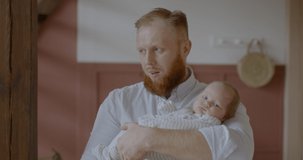 Caucasian father standing tired in room and holding his cute newborn baby laying in his arms. RAW Graded footage 4K slow motion 50fps