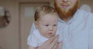 Portrait of a cute caucasian newborn baby hanging on father’s arm. RAW Graded footage 4K slow motion 50fps