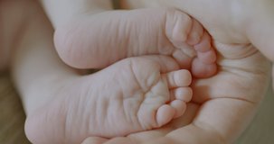 CU of feet of cute caucasian newborn baby in palm on her mother. RAW Graded footage 4K slow motion 50fps