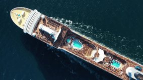 Aerial top down tracking video of large cruise liner ship with huge swimming pools on top cruising deep open ocean sea