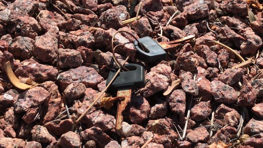 guy picking up a set of rusty old keys in the middle of the desert. 