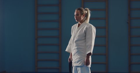 Preparing a fighter for training and battle. Girl in a white kimono ties a belt.