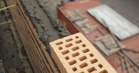 Close-up of fresh masonry, bricklayer puts brick into masonry wall, professional