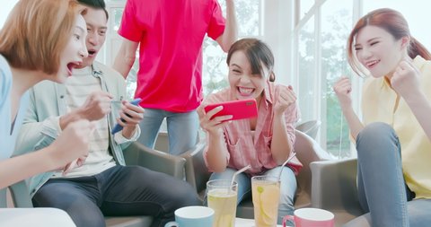 asian woman play games on smart phone and friends are happily