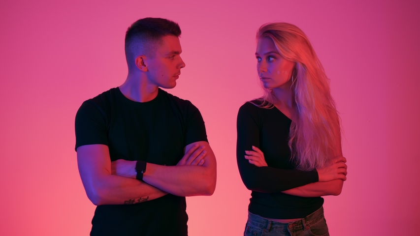 Concept of couple problems in communication. Boyfriend and girlfriend are disappointed and do not want to look at each other. Neon style colors and light at background in studio