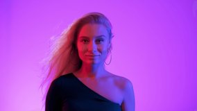 Vivid neon style light. Young blond woman flirting with camera on pink rose gradient background. Happy attractive girl touches her hair and smiles to audience. Close up fashion model looking at camera - Powered by Shutterstock - Get 15% off with code: PIKWIZARD15