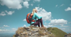 Woman backpacker tourist traveler camper her hands up on top of mountain in summer sunny day under sun light. Beautiful mountains landscape view. 4K slow motion video