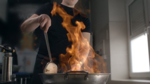 Chef fries asian food in hot flaming wok in slow motion, cooking chinese cuisine, stirring in a hot pan, kitchen of the chinese fast food restaurant, slow mo cooking, Full HD Prores HQ 10 bit in 240