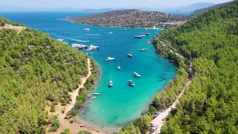 yachts anchored at a green and turquoise-colored Mediterranean coast, zooming in, drone footage