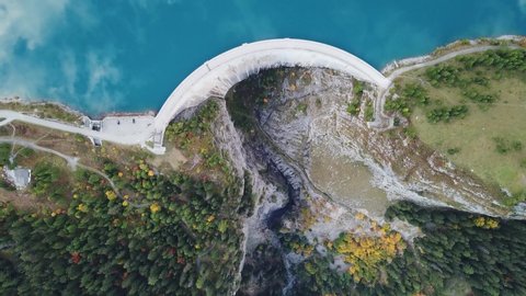 Hydroelectricity generated from water dam and reservoir lake in Swiss Alps mountains to produce renewable energy and limit global warming, sustainable hydropower, aerial drone footage 4K 60fps video