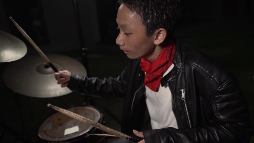 Teenager rock band drummer . cool and talented Asian American mixed young boy playing drums in leather jacket performing song in dark background feeling super star on stage
 | Shutterstock HD Video #1038312386